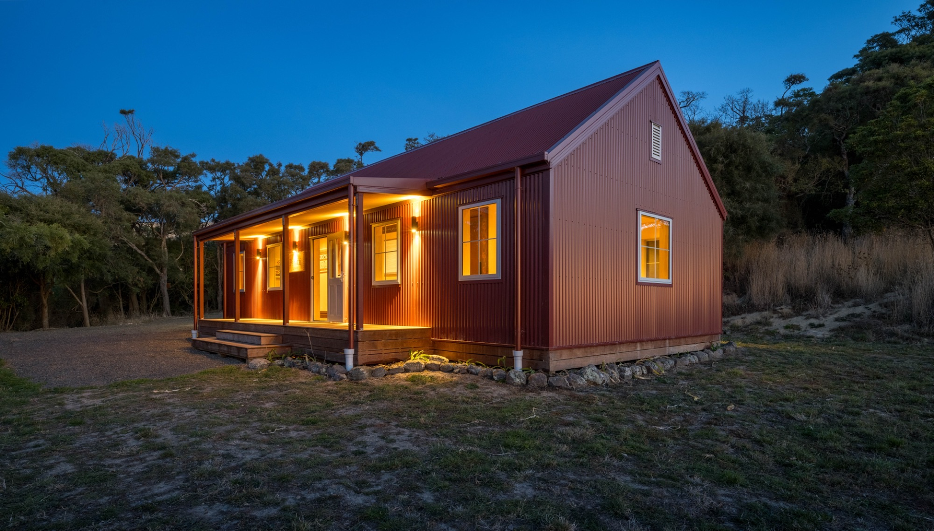 The Rehutai Museum at dusk — a gabled building with a deep verandah, its windows glowing warmly.